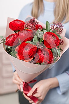 Sunny spring morning. Young happy woman holding a beautiful bunch of red buttercups or Ranunculus in her hands. Present