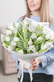Sunny spring morning. Young happy woman holding a beautiful bunch of white tulips in her hands. Present for a smiles
