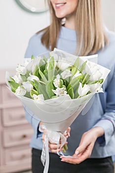 Sunny spring morning. Young happy woman holding a beautiful bunch of white tulips in her hands. Present for a smiles