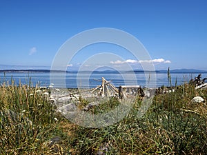 Sunny Summer day on a rocky beach with a Driftwood Tipi Tent like figure in the distance