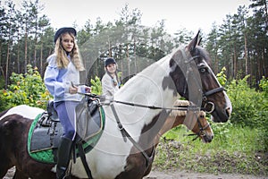 On a sunny summer day  two girls are riding a horse