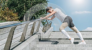 Sunny summer day. Young woman doing stretching exercises outdoor. Girl doing warm-up on steps before training. Workout.
