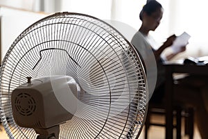 Sunny summer in front of the working fan, suffering from the summer heat. Unhappy Asian woman sitting in front of fan at work