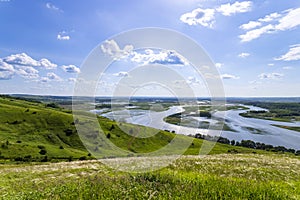 Sunny summer landscape with river,fields,green hills and beautiful clouds in blue sky.Pretty view of summer scenery on a