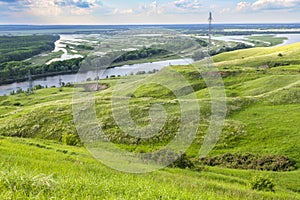 Sunny summer landscape with river,fields,green hills and beautiful clouds in blue sky.Pretty view of summer scenery on a