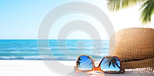 Sunny tropical beach vacation background; glasses and palm tree reflex