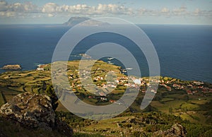 Sunny view of Sao Miguel, Azores island. Background of green fields, cosy village, blue ocean water and neighbour island