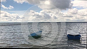 Sunny weather on a freshwater lake. On the waves rock boats and catamarans. In the blue sky lush clouds.