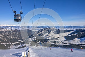 Slunečné počasí nad sjezdovkou a panorama zasněžených hor
