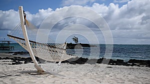 Sunny and windy paradise beach with traditional braided hammock.