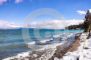 Sunny winter day on the shoreline of Lake Tahoe, Sierra mountains, California; breaking surf created by the wind crashing on the