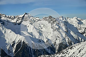 Sunny winter day in Tyrol Alps: snow covered mountain slopes and blue sky.