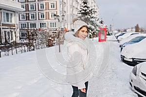 Sunny winter morning of amazing pretty girl walking on street full with snow. Cold weather, christmas mood, brightful