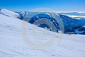 Sunny Winter Over Mountain Peaks and Wide Ski Slope