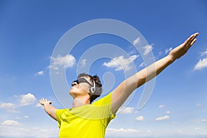 Sunny young man enjoying music with blue sky