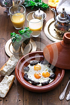 Sunnyside Eggs cooked in a Tajine dish with beef, Moroccan breakfast with juice and mint tea