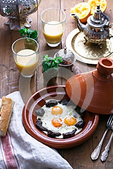 Sunnyside Eggs cooked in a Tajine dish with beef, Moroccan breakfast with juice and mint tea