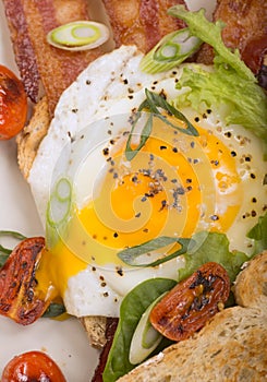 Sunnyside up egg on bacon and toast
