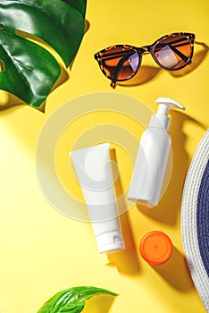 Sunprotection objects. Hat and sunglasses, protection cream SPF Flat lay on yellow background. Beach accessories