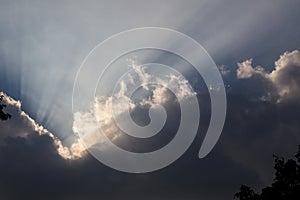 Sunrays coming out of silhouetted clouds during sunset