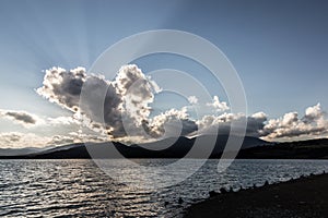 Sunrays through dark clouds above Montedoglio lake Tuscany, Italy