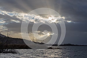 Sunrays through dark clouds above Trasimeno lake Umbria, Italy