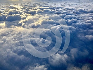 Sunrise above clouds from a plane window. Beautiful blue sky and fluffy clouds view from the airplane.