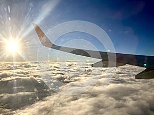 Sunrise above clouds from a plane window. Beautiful blue sky and fluffy clouds view from the airplane.