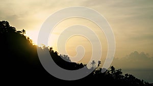 Sunrise in Bali. Indonesia. The sun comes out from behind the mountain, with palm trees on top