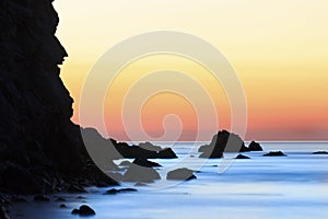 Sunrise on beach with rocks and sea