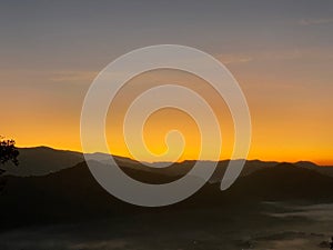 Sunrise behind mountain in the morning with magnificent mist landscape in winter season.