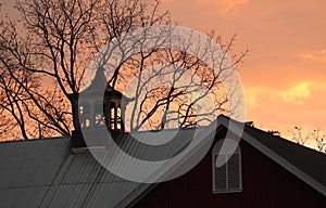 Sunrise behind vintage historic wood barn louvered cupola photo