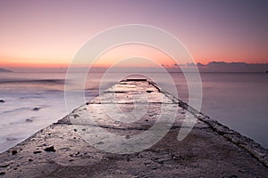 Sunrise on Black sea rocky shore with old pier