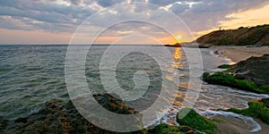 sunrise at the black sea. wonderful calm landscape with rocks on the beach beneath a cloudy sky