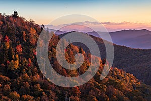 Sunrise on the Blue Ridge Parkway in Autumn illuminating colorful trees on the hillside.