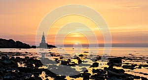 Sunrise on the Bulgarian Black Sea coast in Athopol with the harbor lighthouse and rocky shore