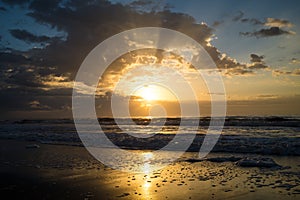 Sunrise with Clouds and Beams of Light Over the Beach and Ocean