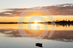 Sunrise clouds reflected warmly on calm harbour water