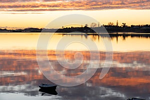 Sunrise clouds reflected warmly on calm harbour water