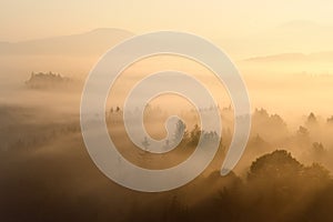 Sunrise in a Czech republic. Golden rays. Foggy morning like a background. Small mountains and their shadows