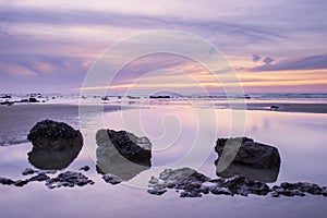 Sunrise dawn landscape on rocky sandy beach with vibrant sky and