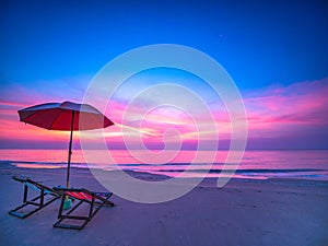 Sunrise with dramatic morning sky over sea with chair and umbrella on beach