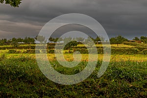 Sunrise with a dramatic sky with an impressing cloudscape over the field and meadows of the village Bemelen