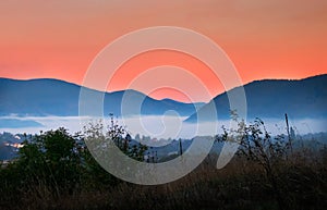 Sunrise with fog, mountains and town in the background