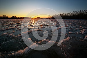 Sunrise and frozen river. Beautiful winter landscape with lake in morning time. Daybreak