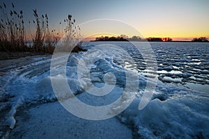 Sunrise and frozen river. Beautiful winter landscape with lake in morning time. Daybreak