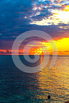 Sunrise glow across ocean framed by dark clouds