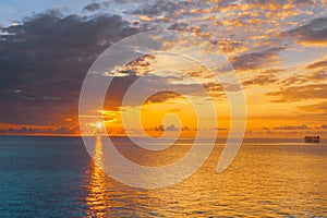 Sunrise glow across ocean framed by dark clouds