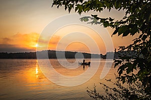 A sunrise greets a lone fisherman on a lake