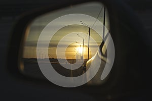 Sunrise on highway road in left side view mirror driver. Focus on reflection in smaller mirror.